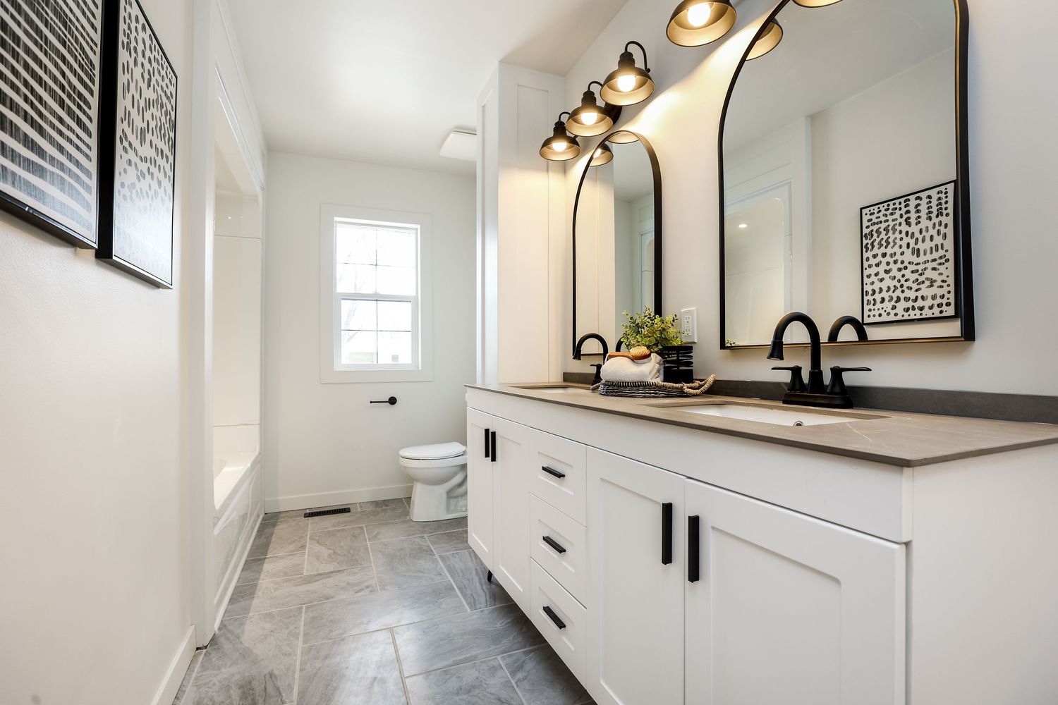 Bathroom with a double vanity, arched mirrors and tile floor