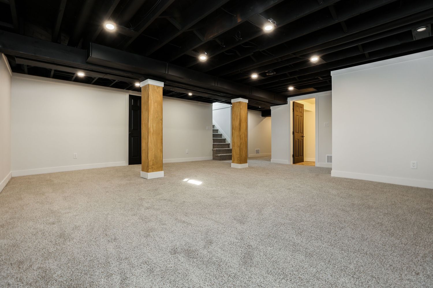 Finished basement with carpet, wood-wrapped posts and pot lights
